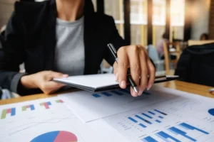 Mujer revisando papeles en un escritorio con un bolígrafo y carpetas